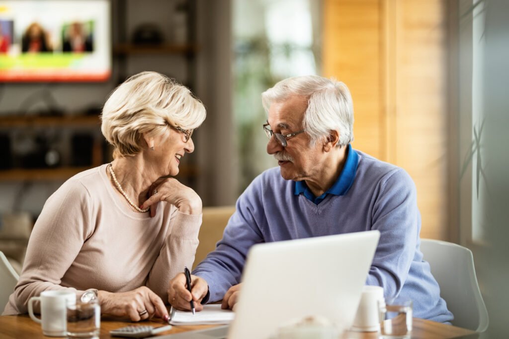 Happy mature couple going through their savings and talking to each other at home.
