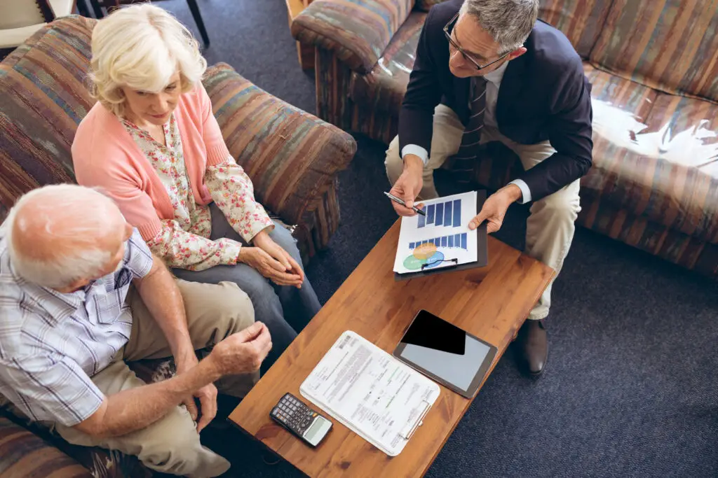 High angle view of Caucasian male physician showing medical statistics to senior couple at retirement home